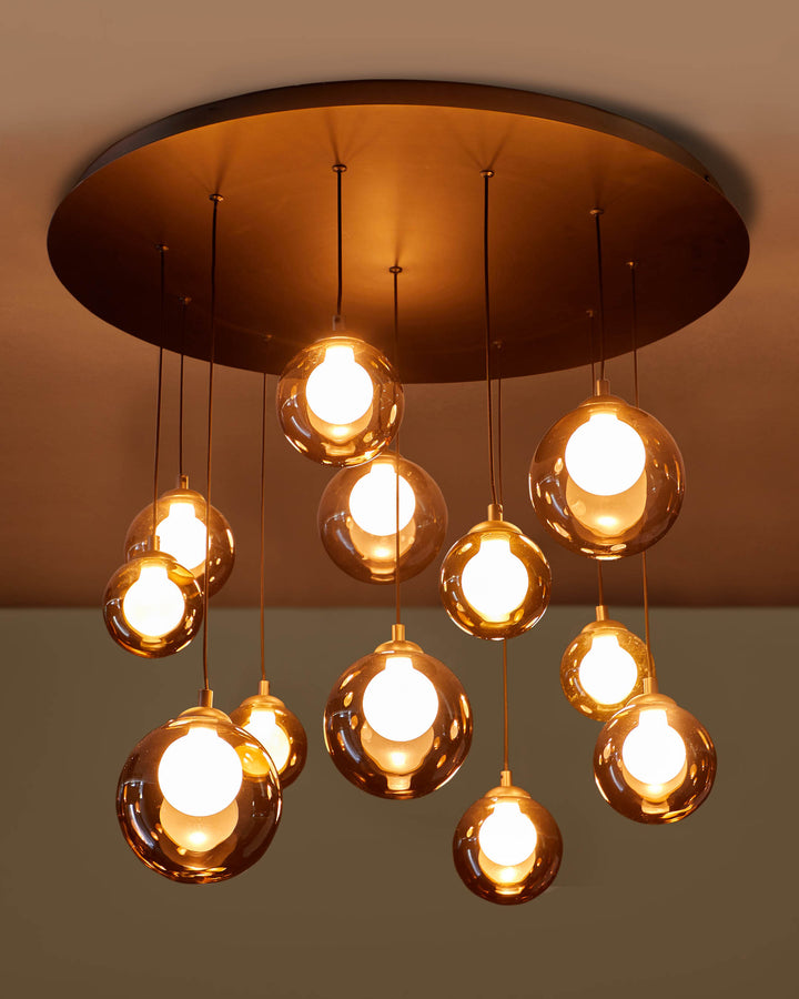 A stylish, contemporary chandelier with multiple illuminated glass orbs hanging from a circular ceiling fixture.