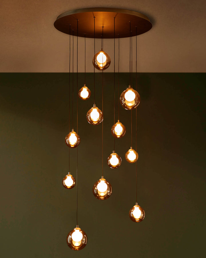 A cluster of pendant lights with amber glass shades hang from a circular bronze ceiling fixture.