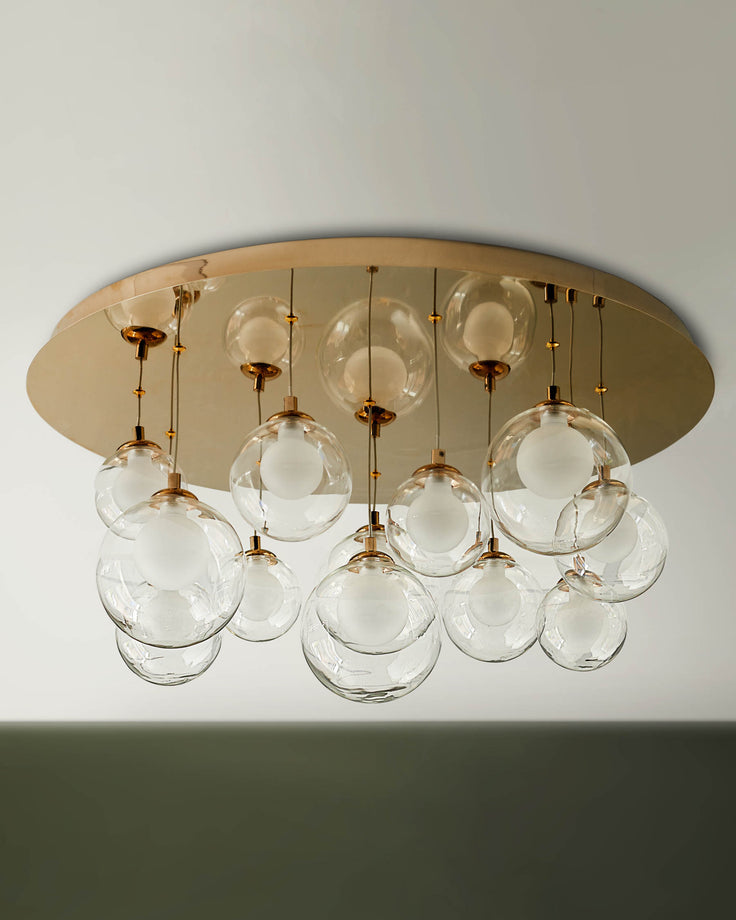 Contemporary ceiling light fixture with transparent glass globes and a gold coloured base plate.