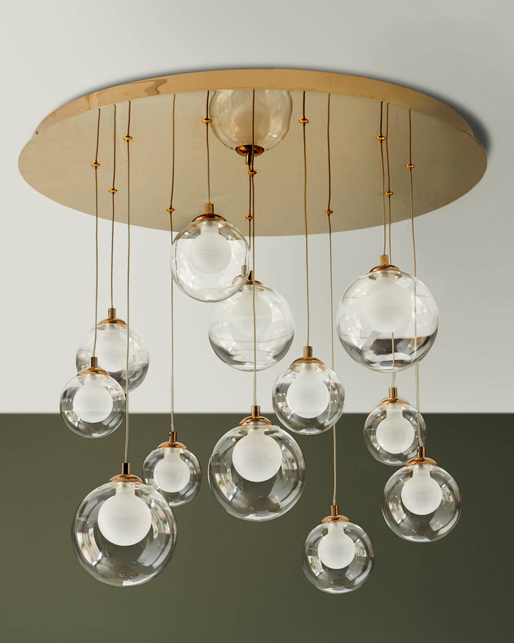 Modern chandelier featuring clear glass globe shades suspended from a gold-tone canopy. A statement lighting piece.