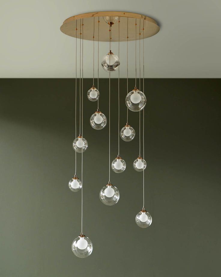 A stylish pendant light fixture with clear glass globe shades suspended at varying lengths from a round gold ceiling canopy.
