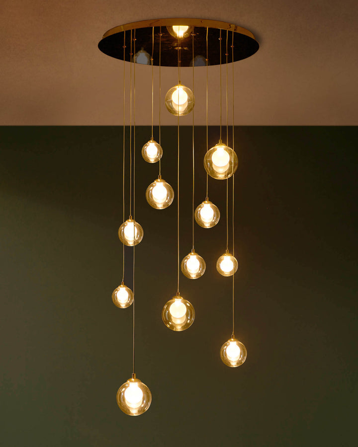 A modern, multi-bulb pendant light with spherical glass shades and golden accents, adding a warm ambience to any room.