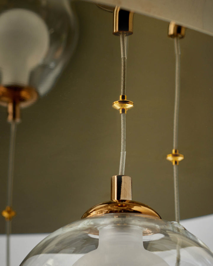 Contemporary pendant light with glass shades and gold hardware, suspended from a modern ceiling fixture.