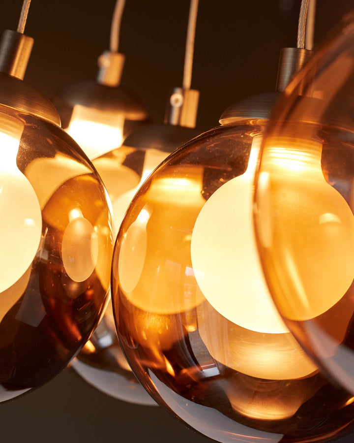 Close-up of a modern, amber glass pendant light with warm-toned bulbs, showcasing a stylish and contemporary design.