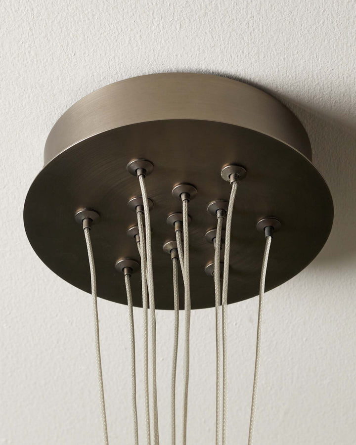 Close-up of a bronze chandelier ceiling fitting with multiple fabric cables dropping down.
