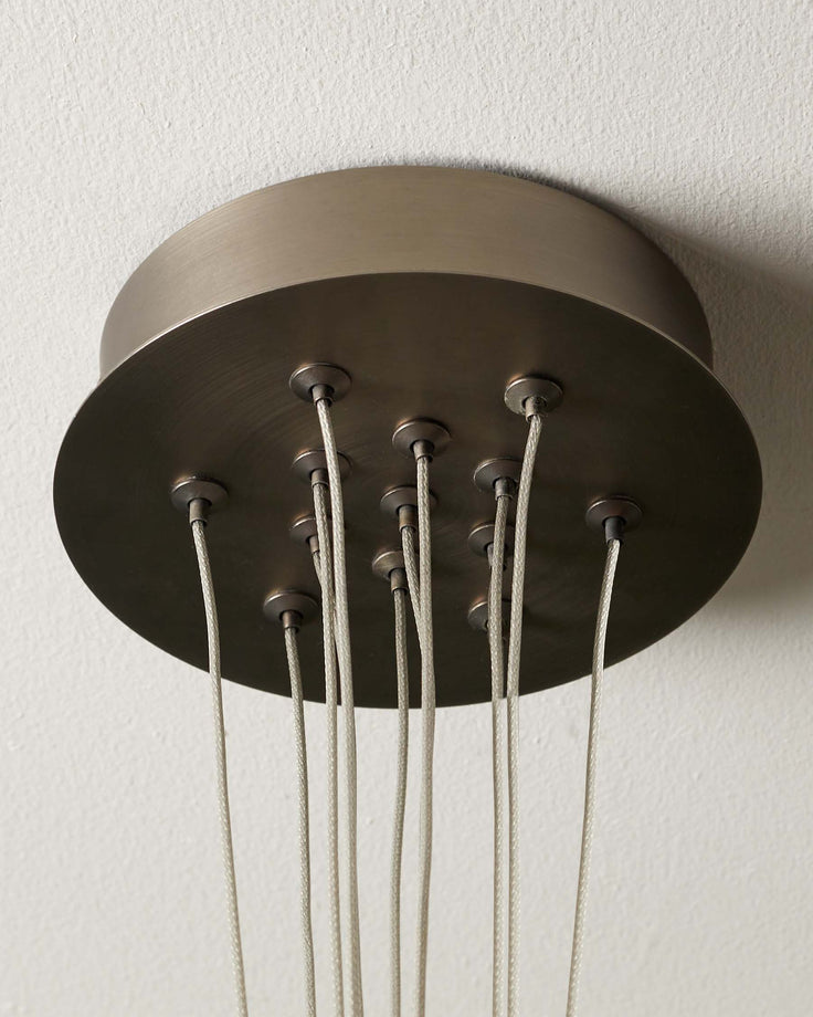 Close-up of a bronze chandelier ceiling fitting with multiple fabric cables dropping down.