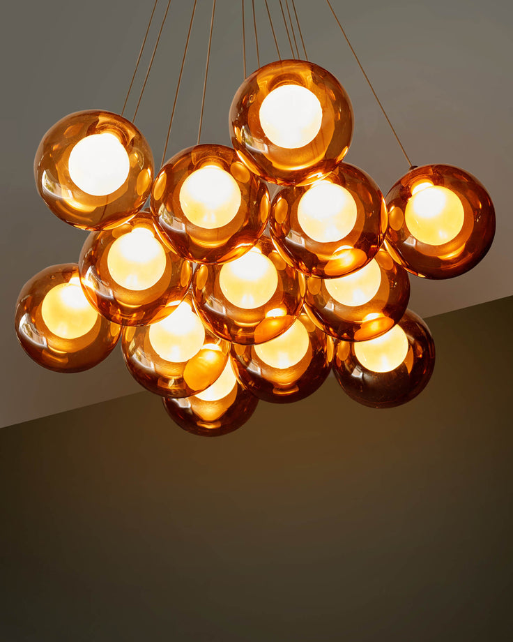 Chandelier featuring amber glass orbs, creating a warm, inviting glow. Ideal for adding a touch of modern elegance to any room.