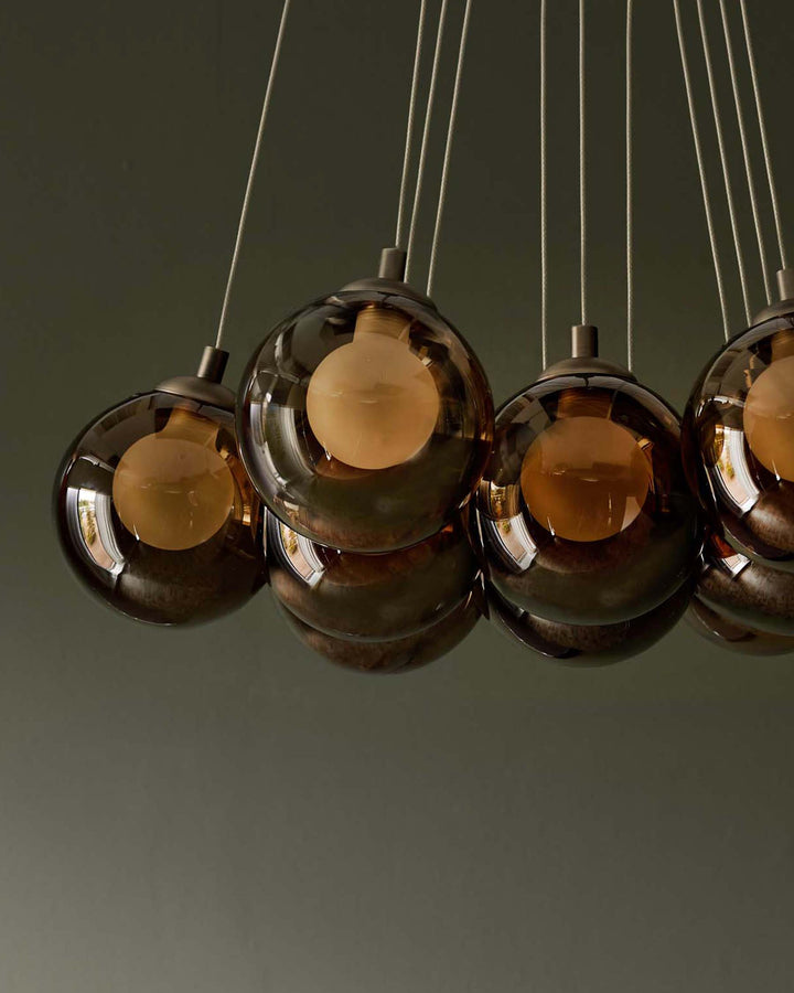 A stylish ceiling light fixture with several round, smoked glass shades and exposed bulbs for a modern aesthetic.