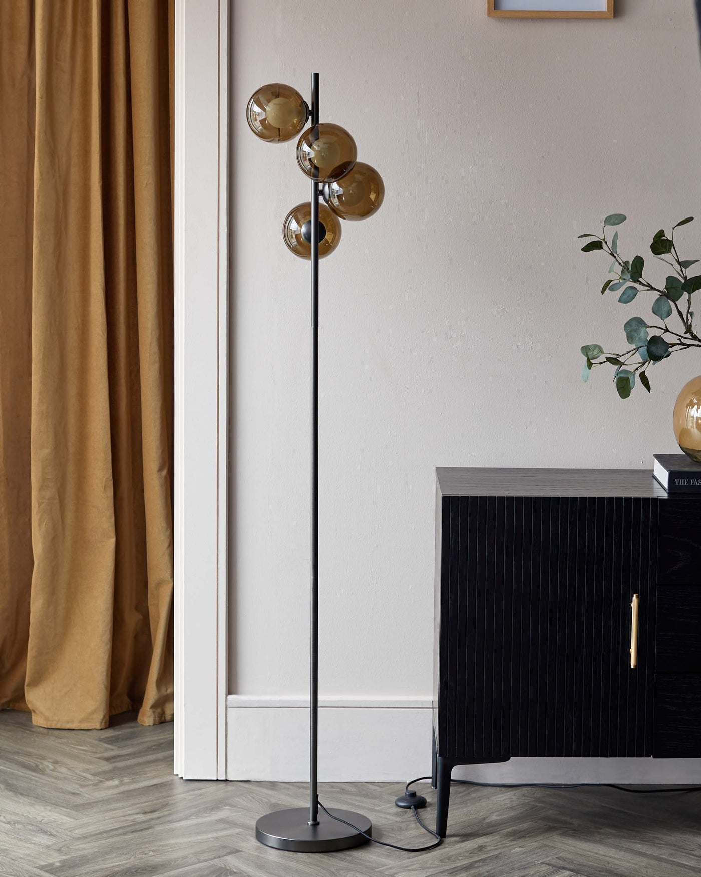 Modern black floor lamp with four globe-shaped amber glass shades positioned at various angles on a central column, paired with a contemporary black ribbed cabinet featuring an elegant brass handle.

Please note that while the image includes a floor lamp, which could be considered a lighting fixture rather than furniture, it is described because it complements the furniture item, the cabinet, in the setting.