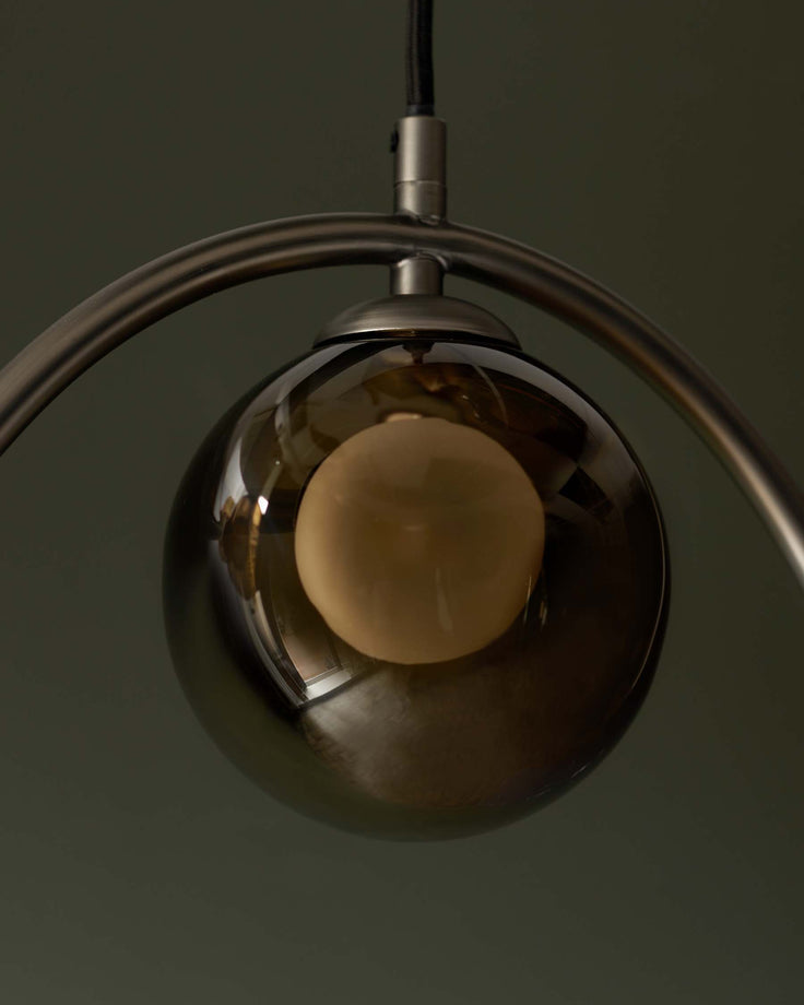 Stylish pendant light with a spherical, tinted glass shade and a warm, inviting glow. Modern design for any interior.