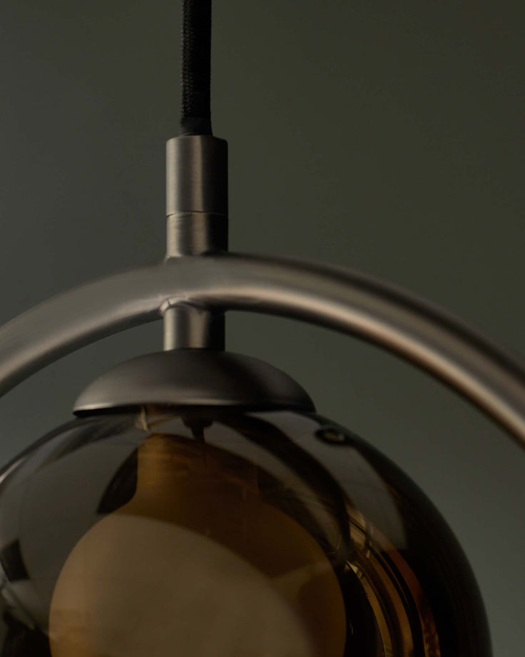 A modern hanging light fixture with a smoked glass globe and brushed metal frame provides a stylish illumination.