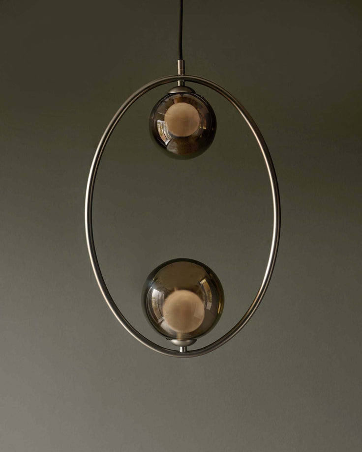 A modern pendant light with two spherical, smoked-glass lamps encased in a metal hoop, suspended from the ceiling.