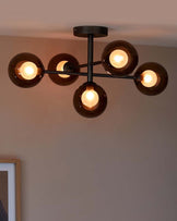 Modern ceiling light fixture with five glass globes, each housing a warm bulb, featuring a sleek metal frame.