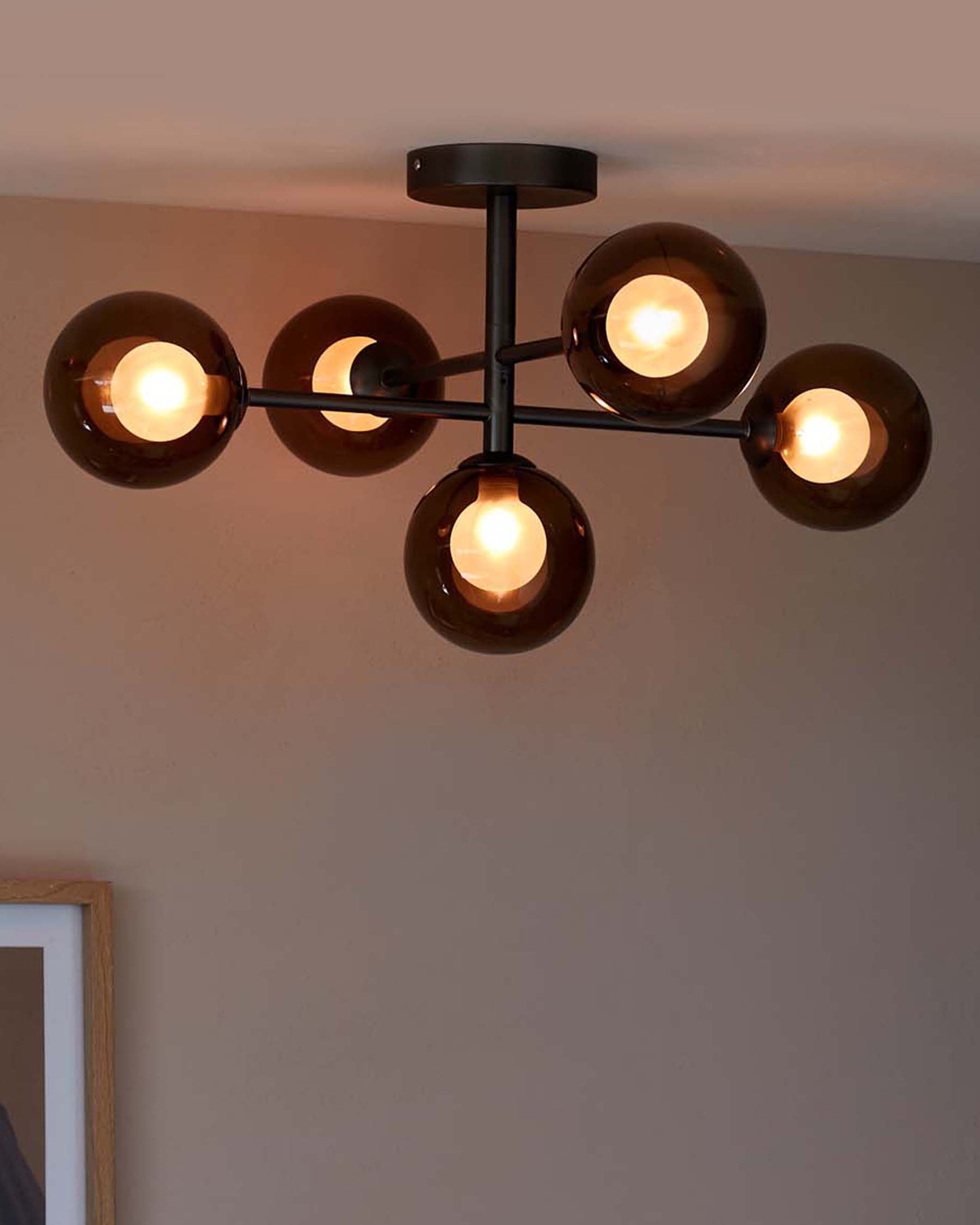 Modern ceiling light fixture with five glass globes, each housing a warm bulb, featuring a sleek metal frame.