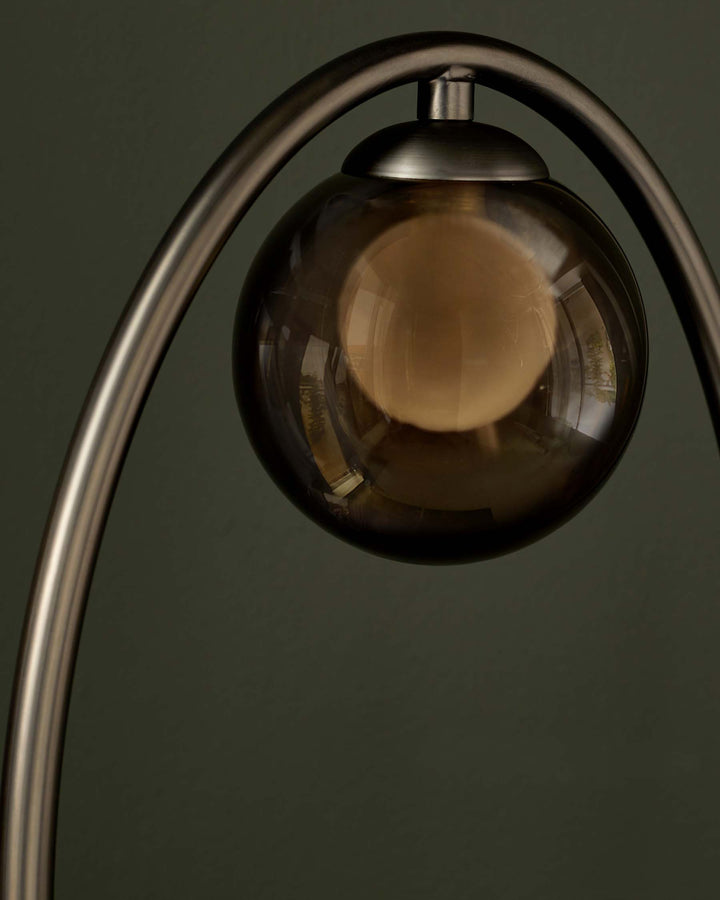 Smoked glass pendant lamp with a smooth, spherical shade and sleek metal arc. Sophisticated lighting for a modern space.
