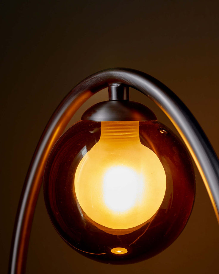 Stylish glass lamp with a curved metal stand. Perfect for adding a touch of modern elegance to any room.