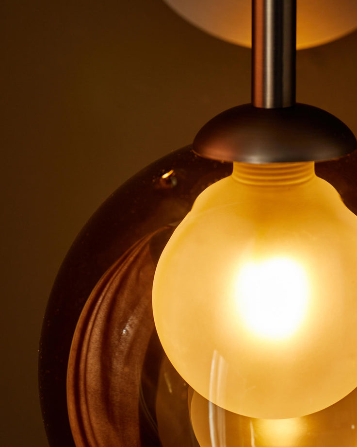 A stylish glass pendant light with a warm glow, perfect for adding ambience to any room.