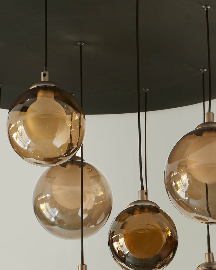 Pendant lighting with amber glass globe shades suspended from a dark-coloured, circular ceiling plate.