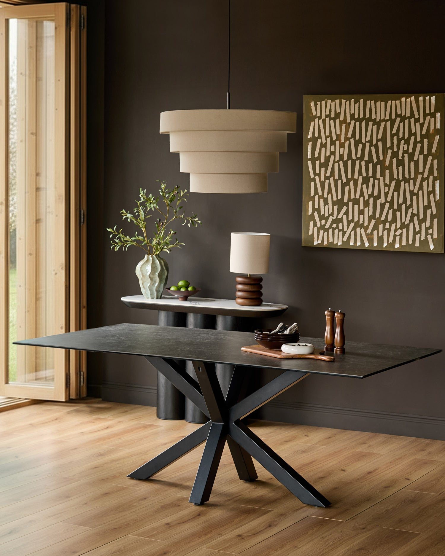 Riley 8-seater dining table with dark grey ceramic top and black metal X-frame base in modern dining room setting.