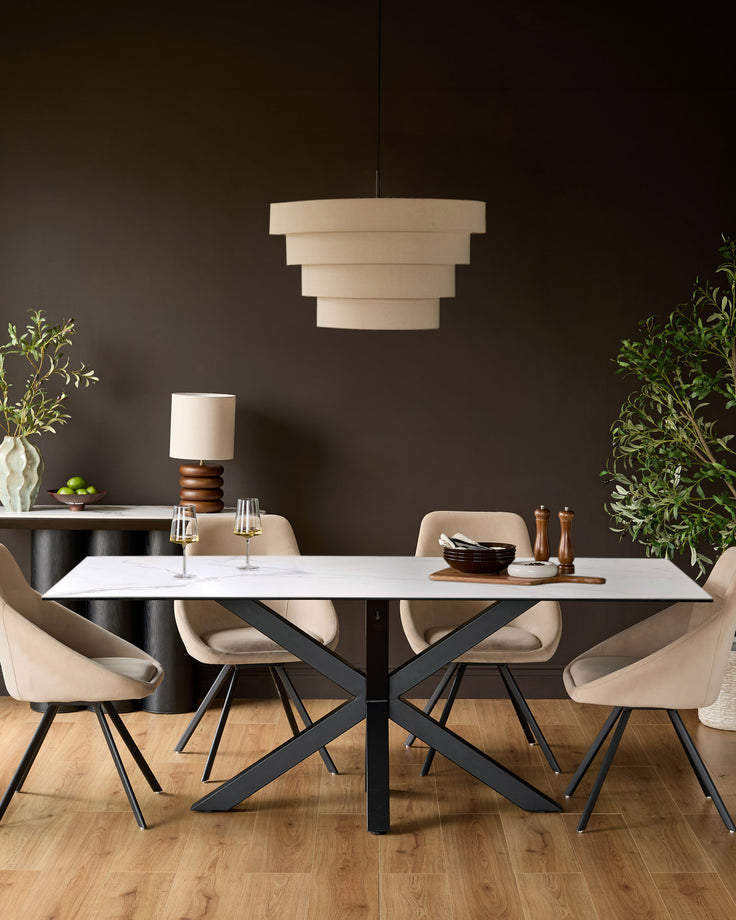 Riley 8-seater dining table in ceramic white with black X-frame base, styled with beige chairs and pendant light.