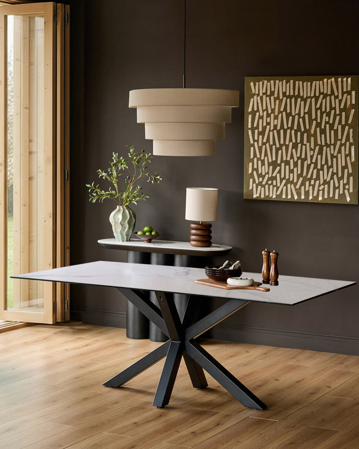 Riley 8-seater dining table with white ceramic top and black geometric star-pattern base on wooden flooring.