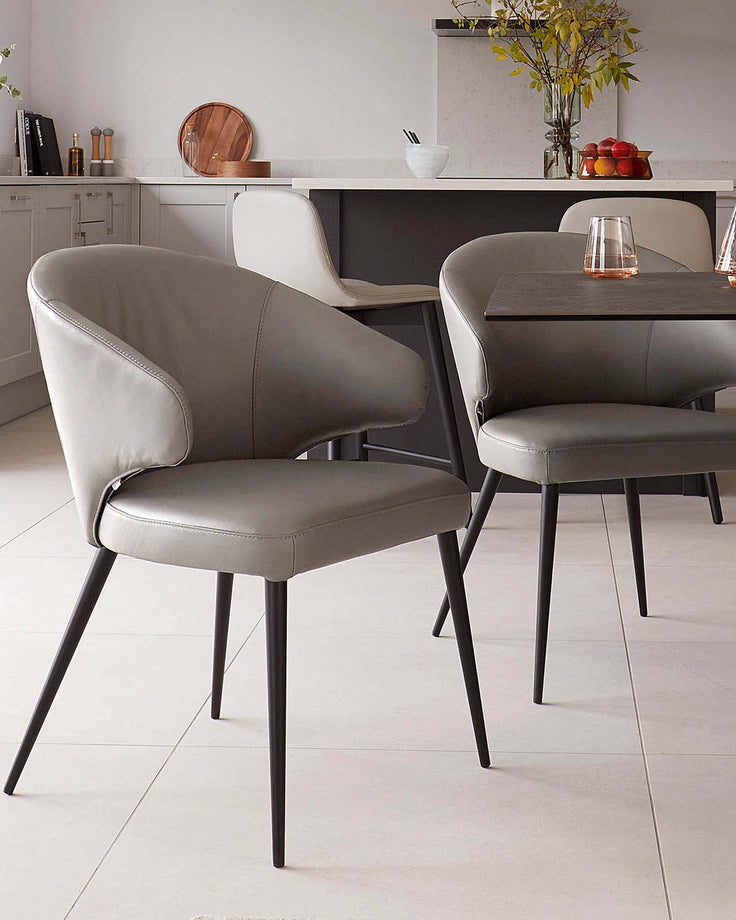 Sleek modern dining chairs with curved leather backs and slender black legs, paired with a stylish tabletop in a contemporary setting.