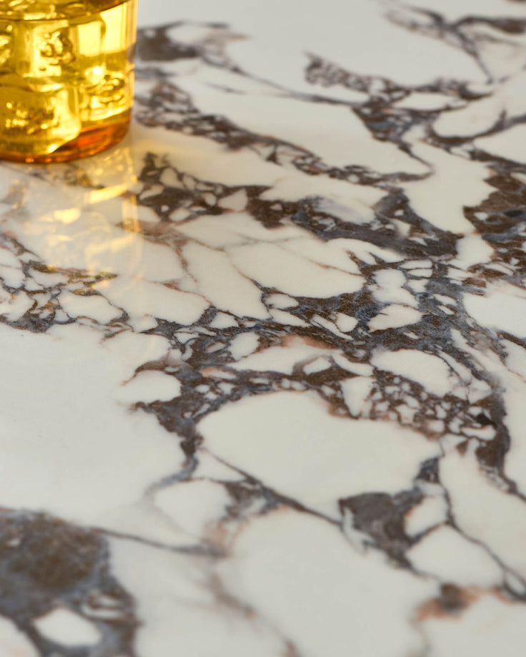 Close-up of a marble tabletop with a golden glass container, showcasing the textures and patterns of the marble.