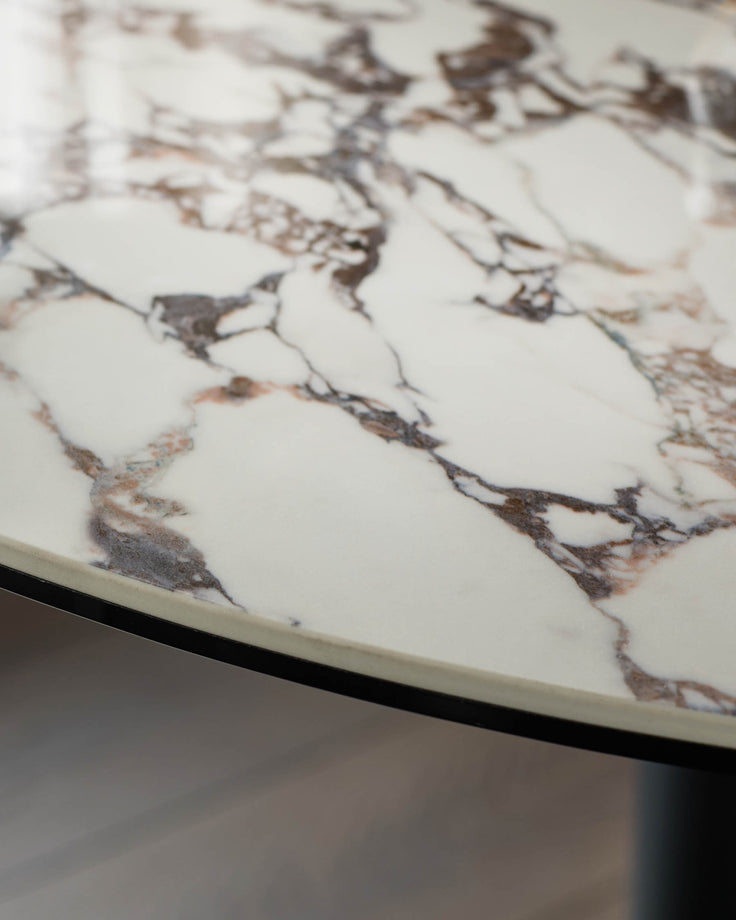 Close-up of a stylish round marble table top with a sleek black rim. A modern furniture piece.