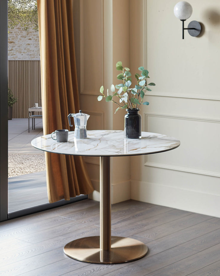 Marble-topped table with a brass-coloured base, styled with a coffee pot, mug and vase with sprigs.