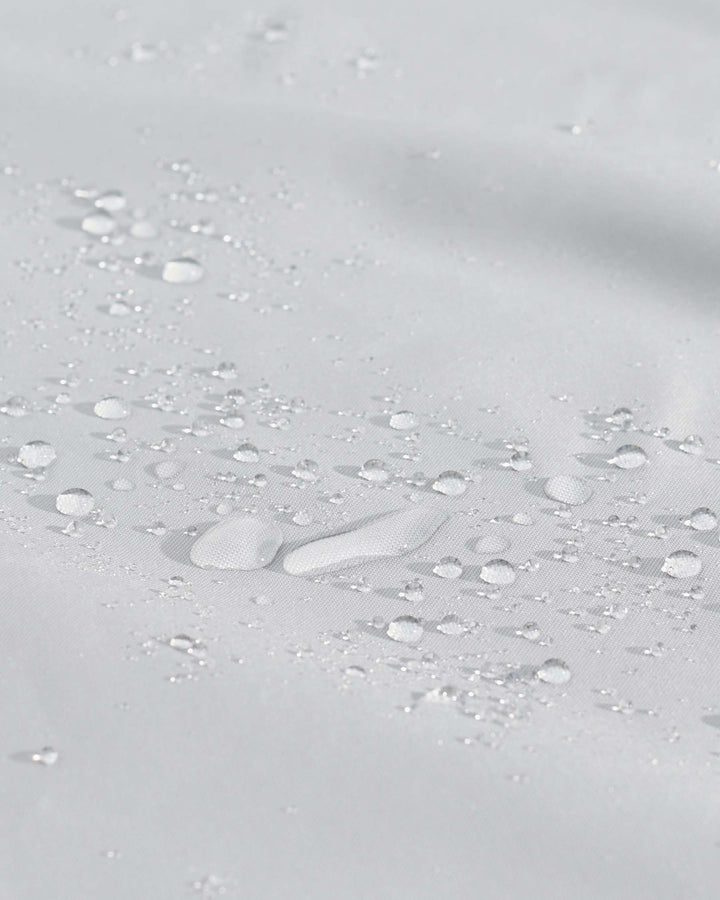 Water-resistant outdoor furniture cover in light Grey with water beads demonstrating protective coating.