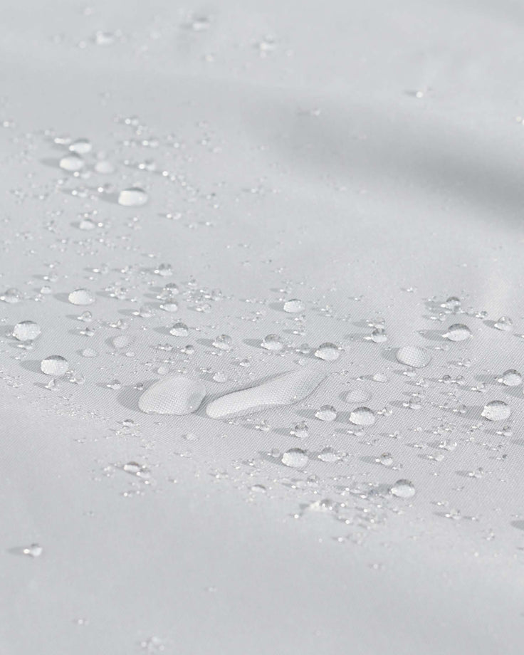 Water-resistant outdoor furniture cover in light Grey with water beads demonstrating protective coating.