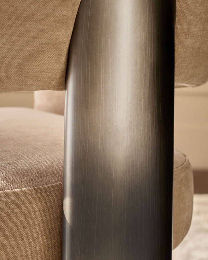 Rosalie dining armchair in champagne fabric, close-up of brushed metal leg detail showing cylindrical frame.