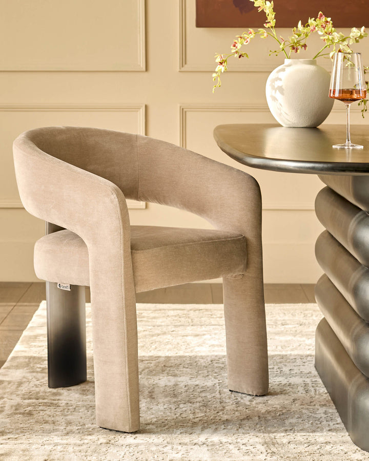 Rosalie dining armchair in champagne fabric, featuring curved wraparound arms and tapered legs, shown in a styled dining setting.