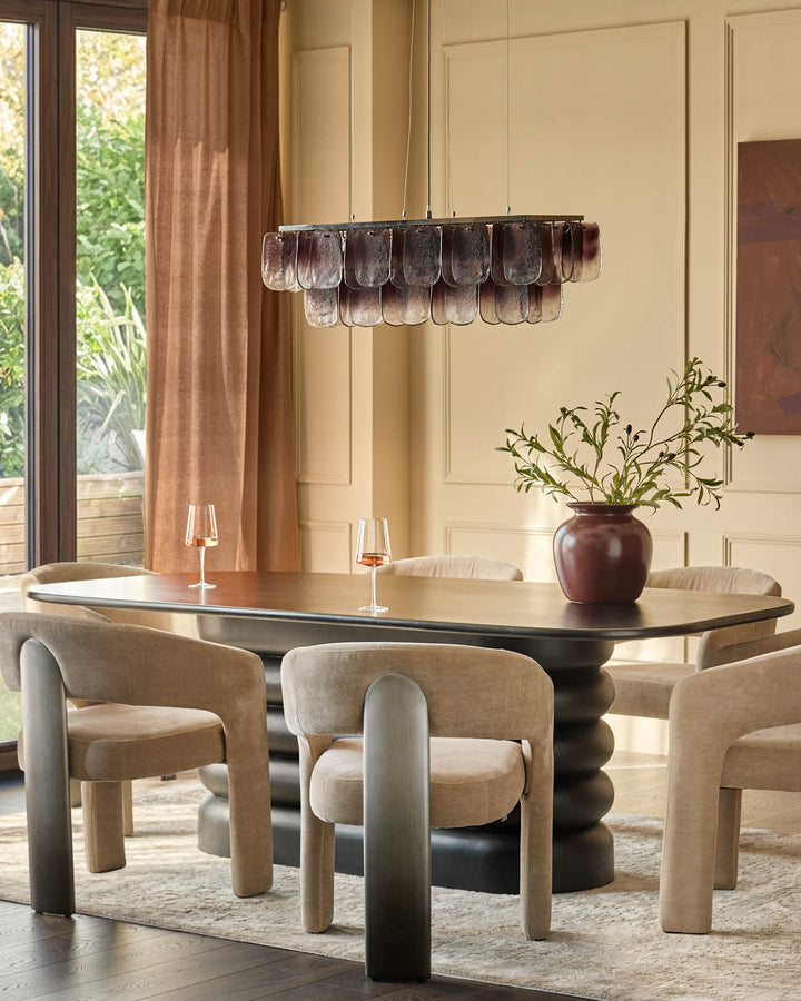 Rosalie dining armchair in champagne fabric with curved wooden frame, shown in a modern dining room setting.