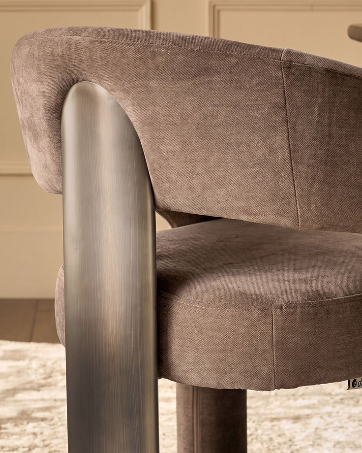 Rosalie dining armchair in mocha fabric with brushed metal armrest, side angle view showing curved backrest and seat.