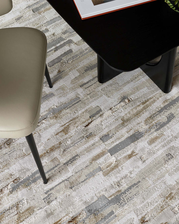A stylish setting with a sleek black table and a contemporary chair, all on a patterned, textured rug.