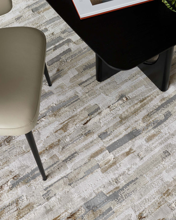 A stylish setting with a sleek black table and a contemporary chair, all on a patterned, textured rug.