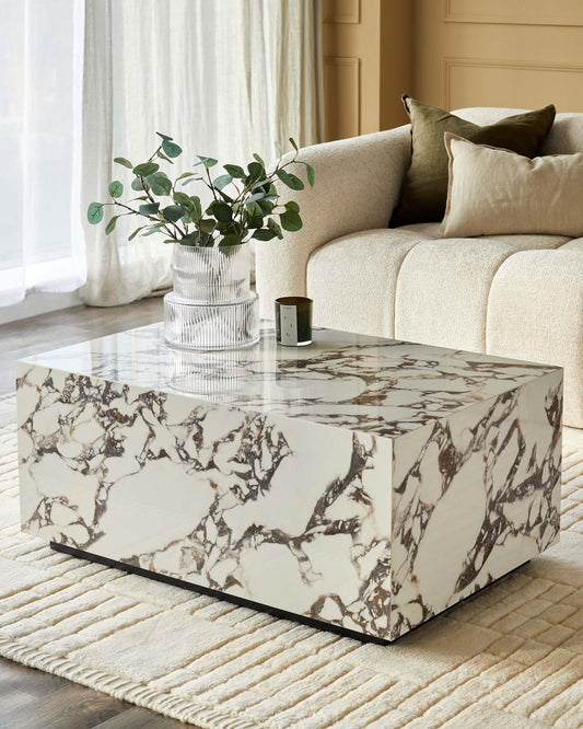 A modern living room with a marble coffee table, stylish sofa and cushions, alongside a decorative vase and candle.