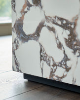 Close-up of a marble effect furniture piece with a dark base, sat on a wooden floor with natural light from a window.