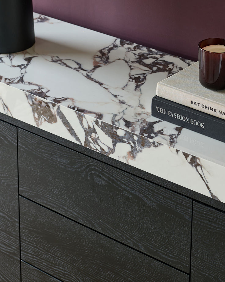Russo sideboard in black wood with Calacatta white marble top, styled with books and candle.