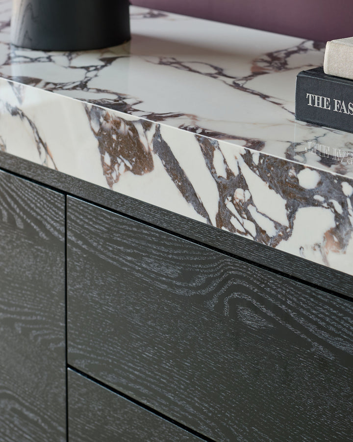 Russo sideboard with dark wood base and white Calacatta marble top featuring brown veining, styled with decor items.