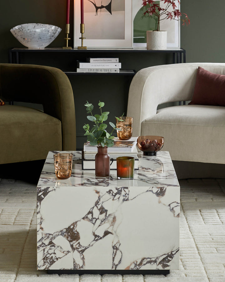 A stylish living room scene showcasing armchairs, a marble coffee table, books and decorative accessories.