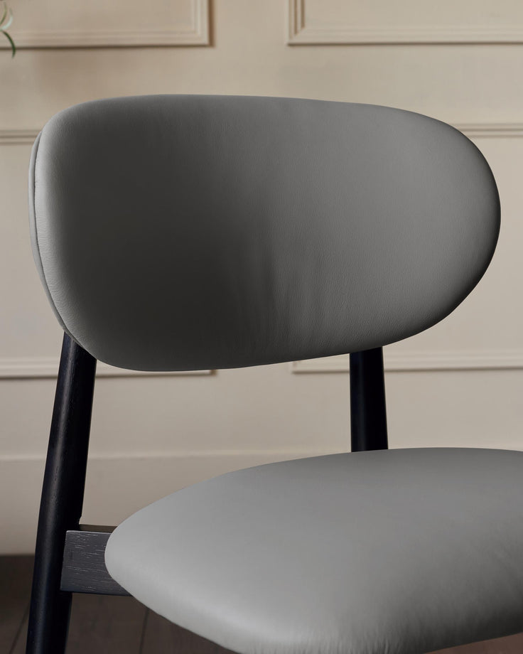 Close-up of a grey chair featuring a rounded backrest and black wooden legs. The design is modern and minimalist.