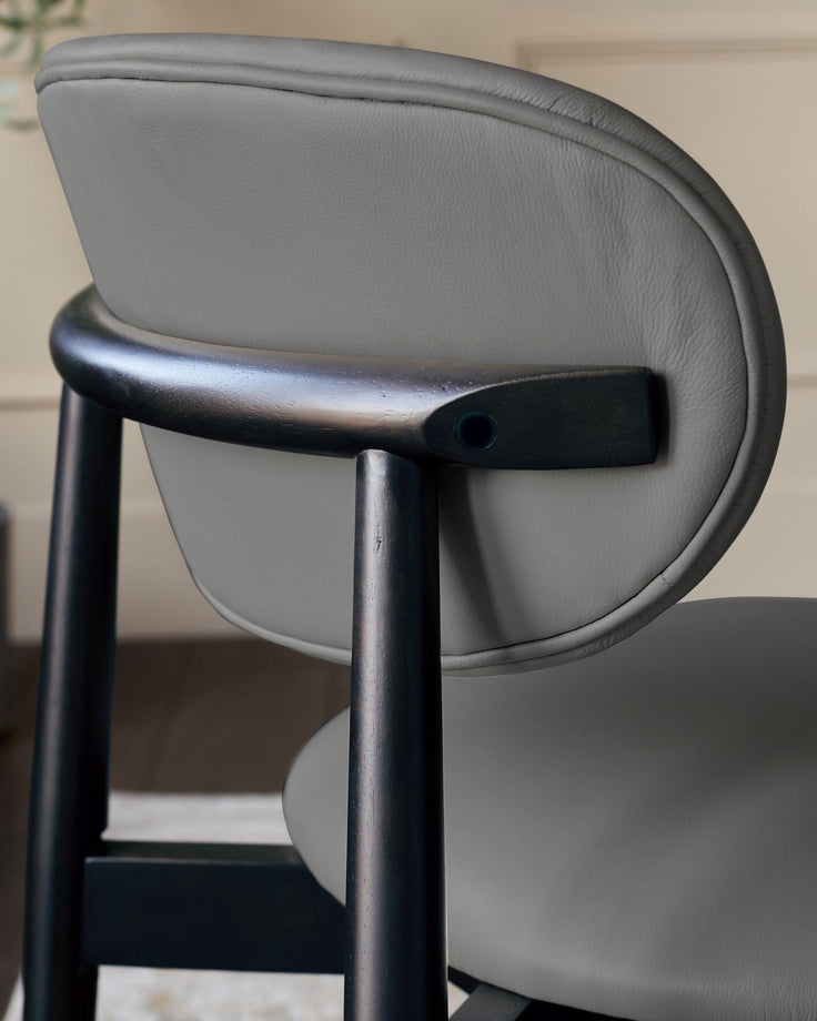 Close-up of a grey leather chair with a dark wooden frame, showcasing its design and craftsmanship.