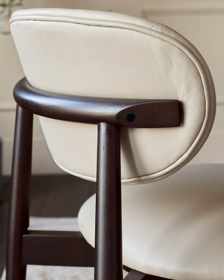 A close-up of a light-coloured leather chair with a curved wooden back support and frame.