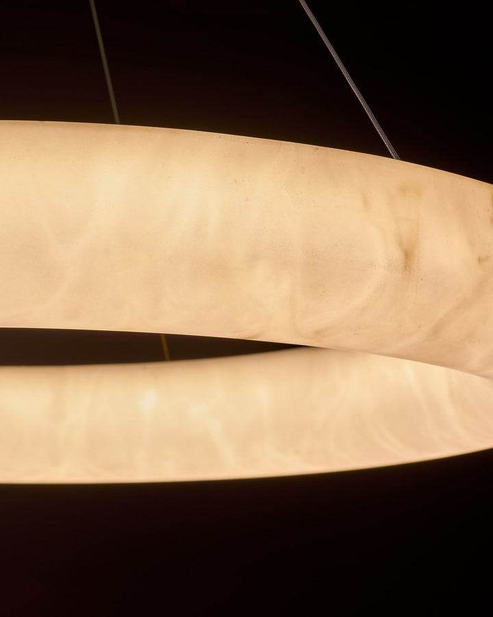 Sadie Large Pendant Light in alabaster effect, showing stacked curved cream-colored bands with warm illumination against dark background.