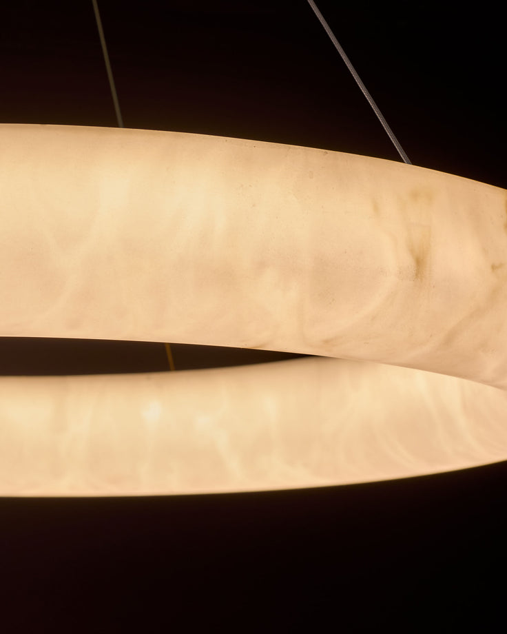 Sadie Large Pendant Light in alabaster effect, showing stacked curved cream-colored bands with warm illumination against dark background.