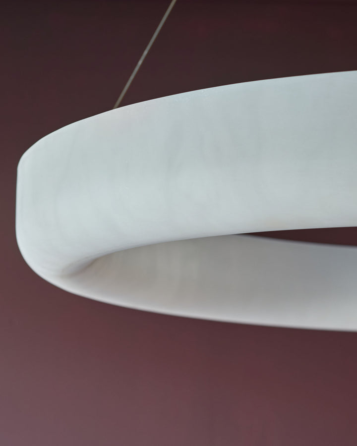Sadie Large Pendant Light in alabaster effect, showing curved white dome shade with cord against burgundy background.