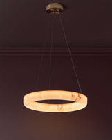 Sadie small pendant light in alabaster effect natural finish, featuring a circular ring design suspended by brass hardware.