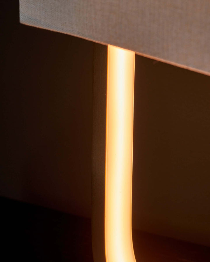 Close-up of a stylish lamp with a beige shade and a sleek, illuminated stand, creating a warm and inviting atmosphere.